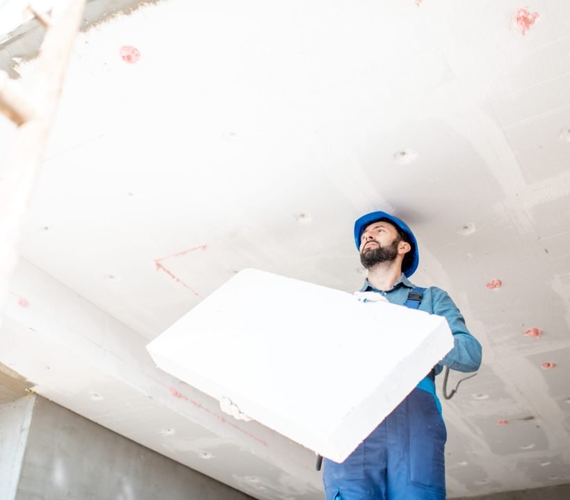 Workman warming the building Builder warming building ceiling mounting foam panels on the construction site